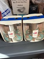 Two sets of USA Collection drinking glasses inside original packaging, each package contains 2 24oz glass tumblers with floral pattern.