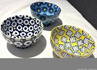 Three ceramic rice bowls with distinct multi-colored floral and geometric patterns, shown on a white surface.