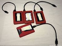 Photo shows four external hard drives in red plastic enclosures with black accents. Three drives labeled 1 TB, one labeled 500 GB, all connected to USB 3.0 cables.