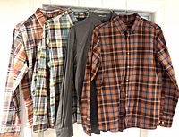 Four shirts hanging on door — three plaids and one gray shirt