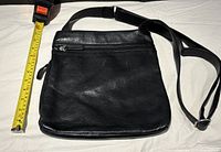 Black leather Osgoode Marley purse/satchel lying flat with measuring tape showing approximate 11 inch height.