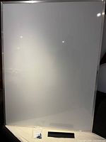 Full view of the large dry-ink whiteboard with black pen holder and mounting hardware at the base.