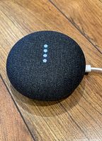 Top view of the Google Nest Mini showing the fabric mesh surface and four white LED indicator lights.