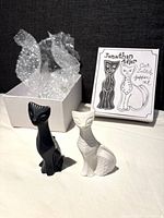 View of black and white cat salt & pepper shakers standing with box and bubble wrap behind.