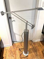 Full view of silver Tizio floor lamp assembled, cylinder base and adjustable arm extended