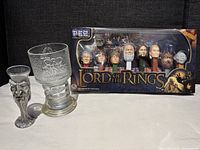 Full view of the Lord of the Rings PEZ set in box, the LOTR glass cup, and the pewter wizard shot glass together showcasing the lot items.