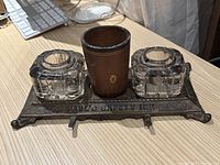 Top-down view of the desk set showing glass ink wells, leather pen holder, and steel base with embossing.