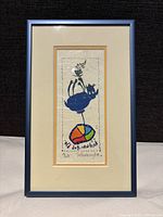 Frontal photo of framed lithograph 'Old Dog New Trick' showing colorful dog on ball artwork with signature and edition number visible.