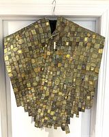 Full view of double sided textile fabric cape in earth tones with square patchwork design and irregular edges