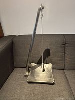 Front side view showing the pendulum suspended from a curved arm above the square tray.