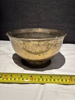 Side view of brass bowl with measuring tape showing width about 8 1/4 inches
