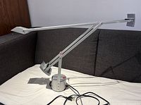 Full view of lamp on sofa showing dual-arm design and powder-coated finish