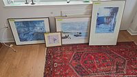 Five framed art pieces arranged on floor by window, including Monet reproductions and floral print