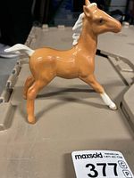 Side view of small Beswick porcelain horse showing tan color with white mane, tail and front hooves