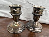 Pair of Birks sterling silver candle holders showing tarnished and patina surfaces with perforated tops.