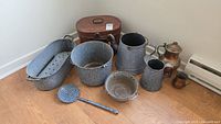 Photo of all enamelware items, painted tin box, and copper pieces on floor showing their condition and features