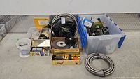 Overview of various electrical and plumbing supplies, including wires, hardware, multiple boxes, and coiled metal flexible conduit.