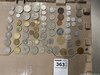 Photo showing a wide assortment of coins from Europe and the Caribbean, arranged by size and type on a beige surface.