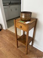 Vintage wooden stand with drawer and open shelf, showing circular cutout on top to hold copper pot.