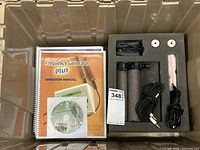 The complete set contained in a plastic bin including the device, cables, accessories, manual, and CD.