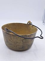 Full view of antique brass jam pot with iron handle from the side