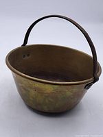 Full view of the antique brass jam pot showing its rounded body and iron handle.