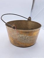 Full side view of the antique Georgian brass jam pot showing the shape and wire handle.