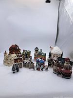 Full view of all porcelain Christmas village buildings and figurines arranged together showing variety in style and size.
