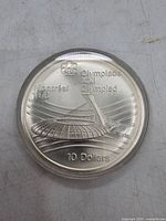 Reverse side of the coin featuring Montreal Olympics 1976 design with Olympic rings, stadium illustration and denomination.