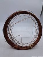 Full coil of copper wire displayed on a clear stand, showing shape and condition with minor bends and wear on wire.