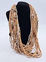 Full view of multi-strand light brown disc and shell bead costume jewelry necklace displayed on black bust