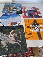 Five LP records laid flat, showing front cover artwork including Igor Stravinsky album with fantasy winged horse and swans, Searching for Sugar Man soundtrack with orange cover and man on stairs, and other vintage style covers.