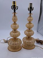 Front view of both amber Murano glass lamps showing stacked gourd shapes and metal socket fittings.