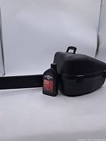 Chainsaw bar cover, oil bottle, case, and partial bar arranged on white background