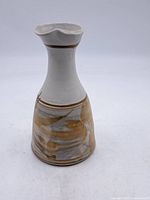 Front view of Robin Hopper glazed ceramic pitcher showing the tall shape with a wide base, narrowing neck, and wavy rim with brown and grey glazes.