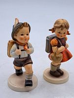Front view of the two vintage Goebel figurines showing school boy and girl side by side