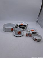 Full lot view showing all porcelain dinnerware pieces with orange circular design.