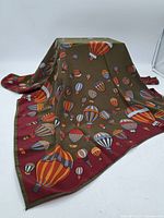 Full view of the silk scarf laid out showing the balloon pattern and the maroon border.
