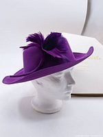 Side profile of the purple felt vintage hat showing the elegant shape and feather decoration.