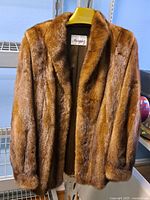 Front view of the brown fur coat on hanger showing texture and style