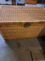 Full front view of woven wicker storage chest with lid closed showing overall chest and lock.
