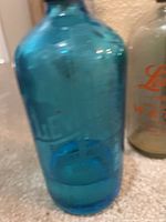 Blue thick glass seltzer bottle with embossed markings, showing color and vintage patina.