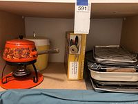 Shelf showing the orange floral fondue pot on its stand with burner, yellow ice bucket, and stacked baking pans and racks