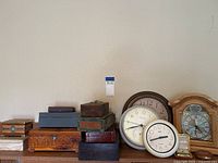 Multiple vintage and antique keepsake boxes stacked with various vintage wall and tabletop clocks visible.