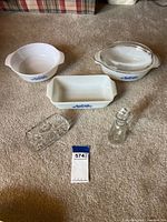 Full view of all items included in the lot: three Corningware casseroles, glass butter dish, and glass oil bottle