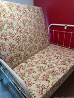Full mattress with floral pattern and white metal bed frame with 5 wood slats visible.