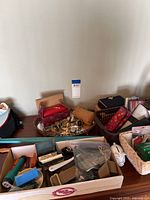Overhead shot of dresser with assorted hats, scarves, jewelry on mirrored tray, shoehorn, glass cases, and baskets.