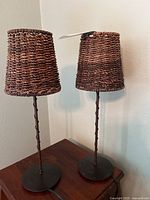 Full view of two small lamps with basket weave shades and metal stands.