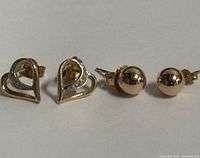 Photo showing the front of the heart-shaped and ball-shaped 10K gold stud earrings
