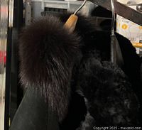 Photo showing part of three vintage fur coats on hangers, with visible damage, wear, and missing buttons